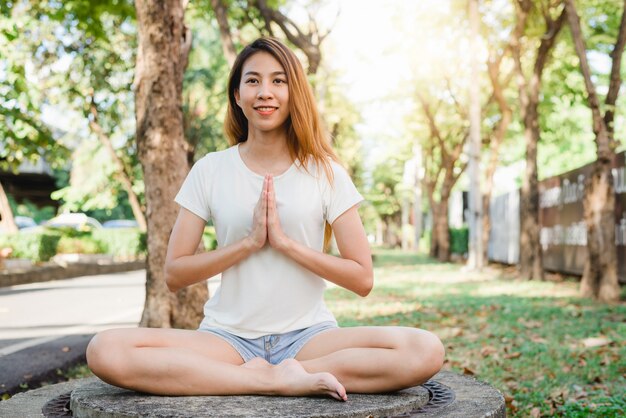 Young asian woman yoga outdoors keep calm and meditates while practicing yoga 