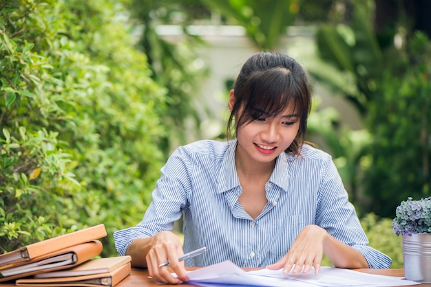 행복 한 감정 개념을 사용하는 여자 야외에서 책상에 숙제를 작성하는 젊은 아시아 여성. 빈티지 효과 스타일 사진.