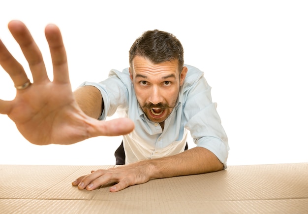 Free photo young astonished man opening the biggest postal package isolated on white wall