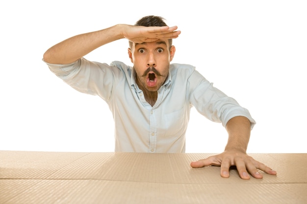 Young astonished man opening the biggest postal package isolated on white