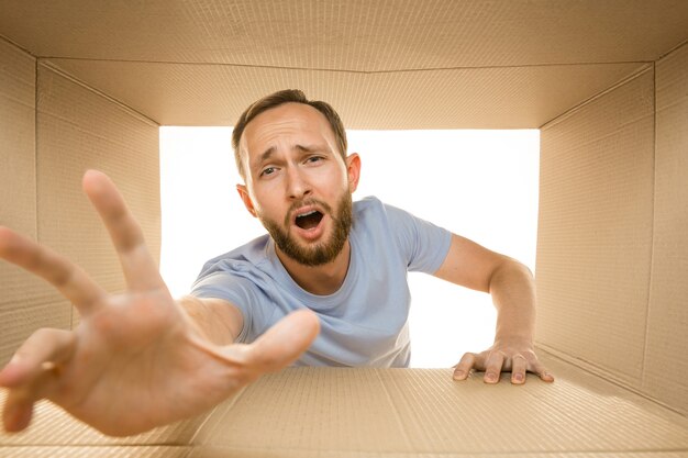 Young astonished man opening the biggest postal package