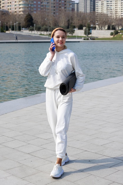 Young athlete holding her mat and talking on the phone High quality photo