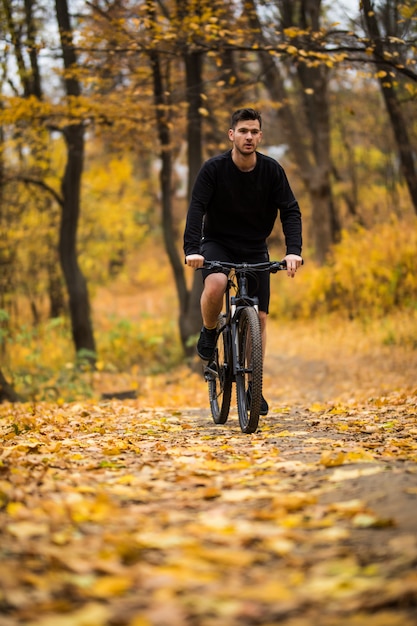 Young athlete man riding sports bike on track in autumn park