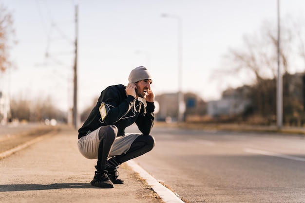 Young athletic man feeling tired and crouching after jogging on the street Copy space