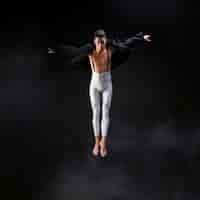 Free photo young athletic man jumping with extended hands near smoke against black background