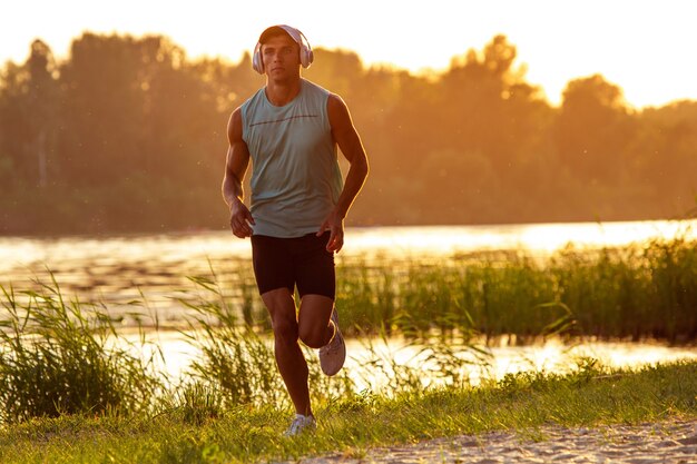 A young athletic man working out listening to the music at the riverside outdoors