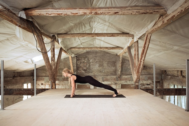 A young athletic woman exercises yoga on an abandoned construction building. Mental and physical health balance. Concept of healthy lifestyle, sport, activity, weight loss, concentration.