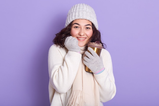 ホットドリンクと手袋のカップを介して彼女の手を浴びて魅力的な女性