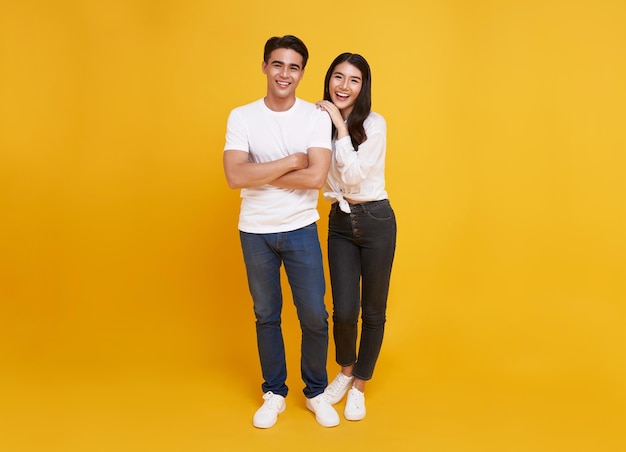 Young attractive Asian couple man and woman happy and hugging on yellow background Concept for love photography