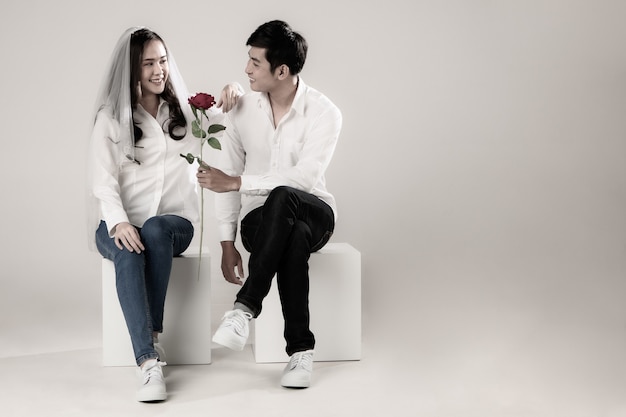 흰색 셔츠와 흰색 배경에 베일을 입고 젊은 매력적인 아시아 부부.