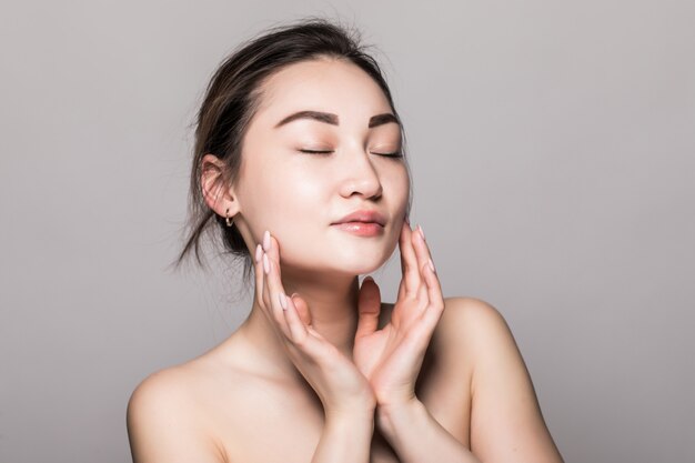 Young attractive asian woman skin care on gray wall