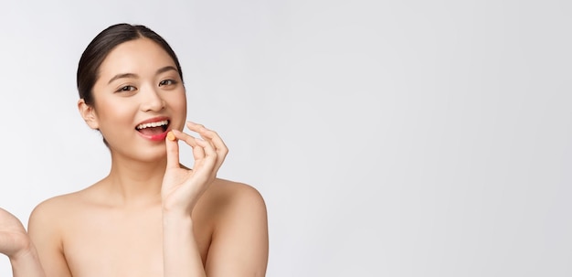 Young attractive asian woman who takes a capsule or pill Isolated over white background