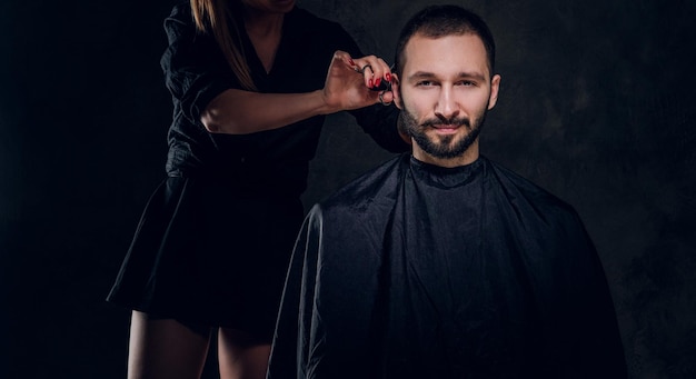 Молодая привлекательная брюнетка посещает парикмахерскую, чтобы позаботиться о своей бороде.