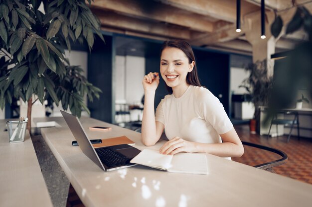 Young attractive businesswoman making notes in notepad at her working place