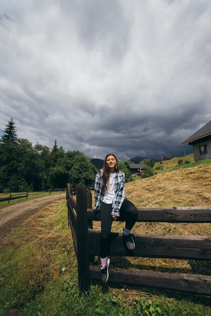 Молодая привлекательная кавказская женщина, сидящая на заборе