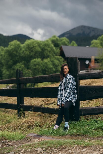 A young attractive Caucasian female stand by a fence and posing at camera