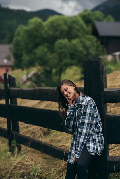 A young attractive caucasian female stand by a fence