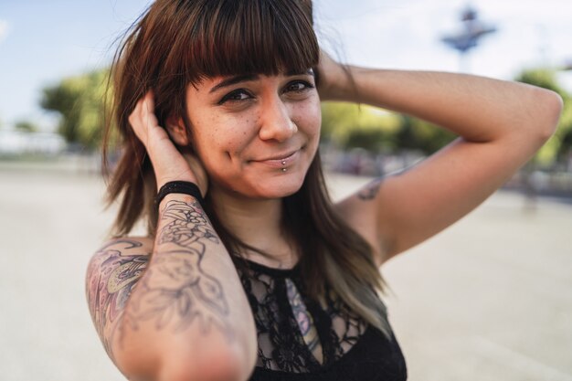 Young attractive Caucasian female with tattoos standing in the street and making a cute face