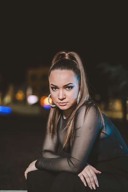 Young attractive Caucasian girl  sitting and posing outside in the evening