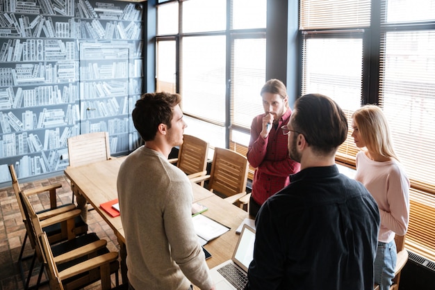 Young attractive colleagues standing while working