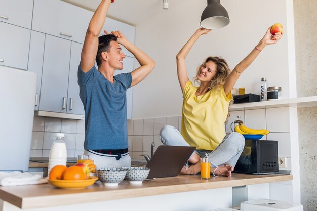 Young attractive couple of man and woman cooking breakfast together in morning at kitchen