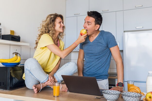 Young attractive couple of man and woman eating healthy breakfast together in morning at kitchen