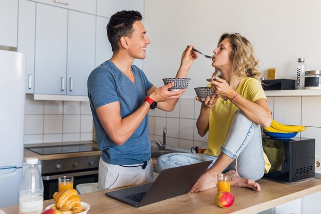 Young attractive couple of man and woman in love eating breakfast together in morning at kitchen