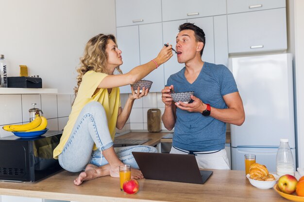 Young attractive couple of man and woman stay home together alone eating breakfast together in morning at kitchen