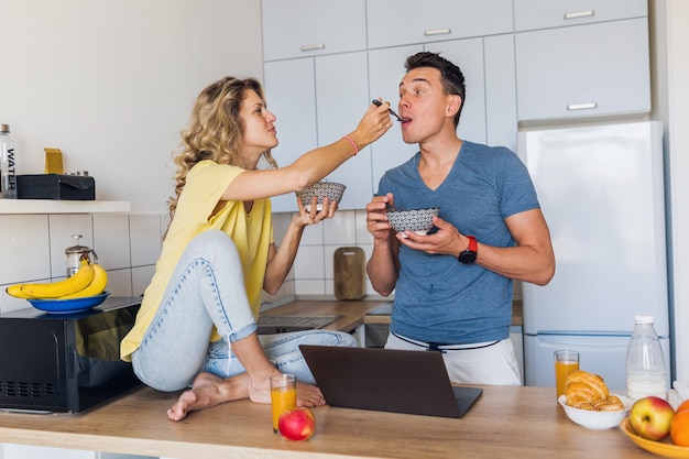 男と女の若い魅力的なカップルは、キッチンで朝一緒に朝食を食べて一緒に一人で家に滞在します。