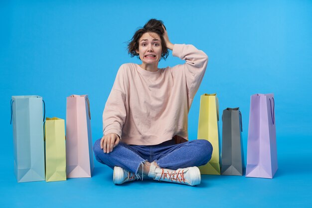 Young attractive dark haired woman with short haircut with a lot of shopping bags