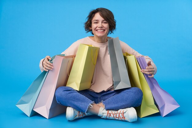 Young attractive dark haired woman with short haircut with a lot of shopping bags