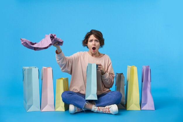 Young attractive dark haired woman with short haircut with a lot of shopping bags