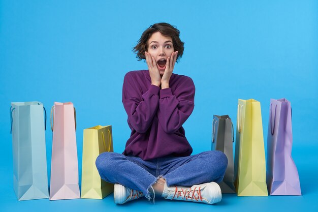 Young attractive dark haired woman with short haircut with a lot of shopping bags