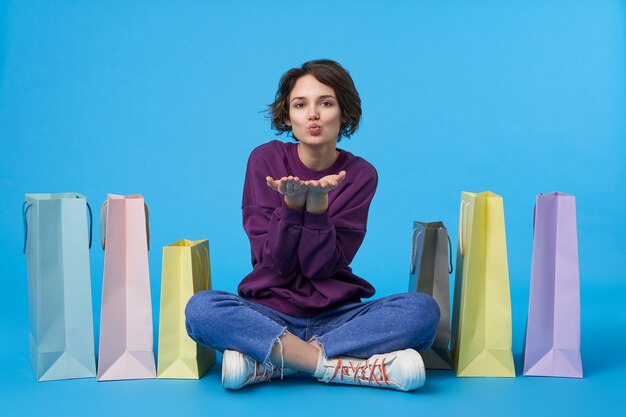 Young attractive dark haired woman with short haircut with a lot of shopping bags