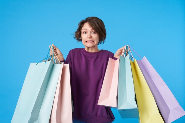 Young attractive dark haired woman with short haircut with a lot of shopping bags