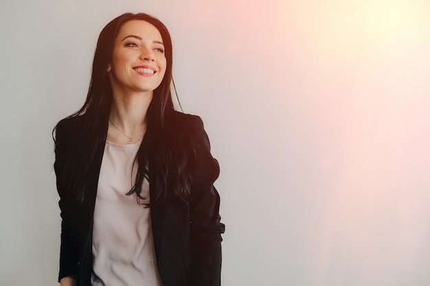 Young attractive emotional girl in business-style clothes on a plain white surface in an office or audience