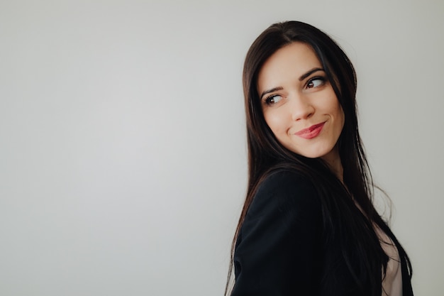 Young attractive emotional girl in business-style clothes on a plain white surface in an office or audience