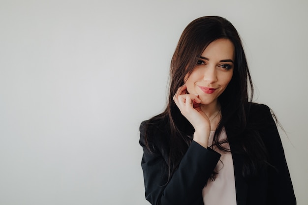 Young attractive emotional girl in business-style clothes on a plain white surface in an office or audience