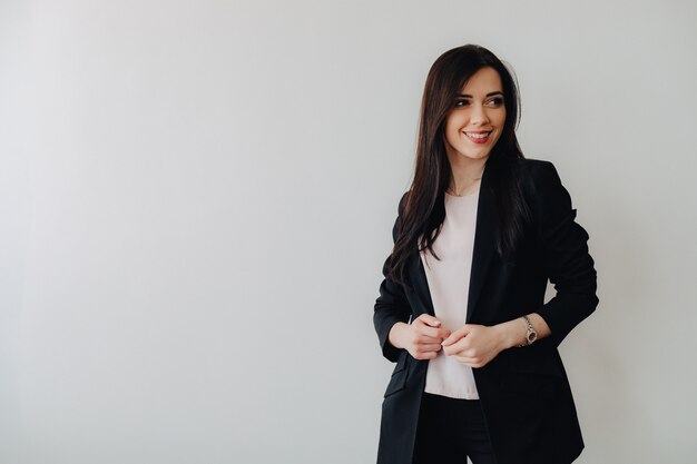 Young attractive emotional girl in business-style clothes on a plain white surface in an office or audience