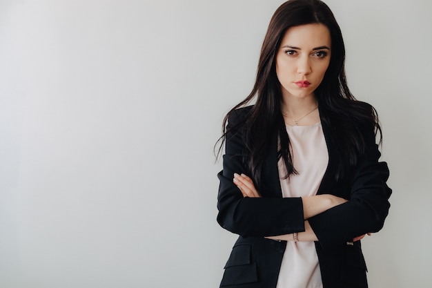 Young attractive emotional girl in business-style clothes on a plain white surface in an office or audience