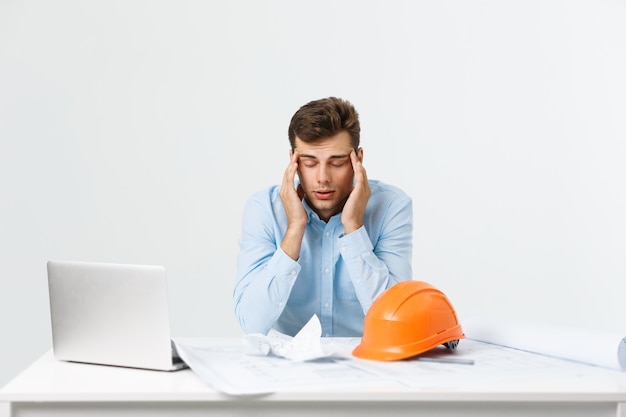 Free photo young attractive engineer man feeling tired at work place