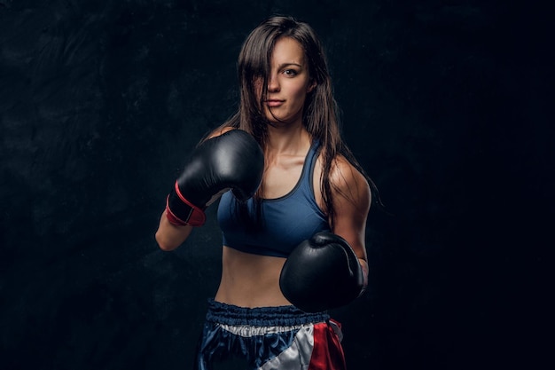 Young attractive female boxer with long hair and boxing gloves is ready to fight.