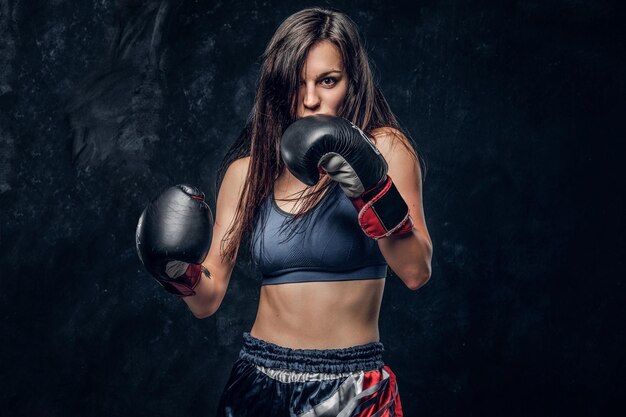 Young attractive female boxer with long hair and boxing gloves is ready to fight.