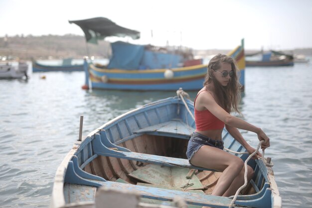 Young attractive female sitting in a wooden boat on the water under the sunlight at daytime