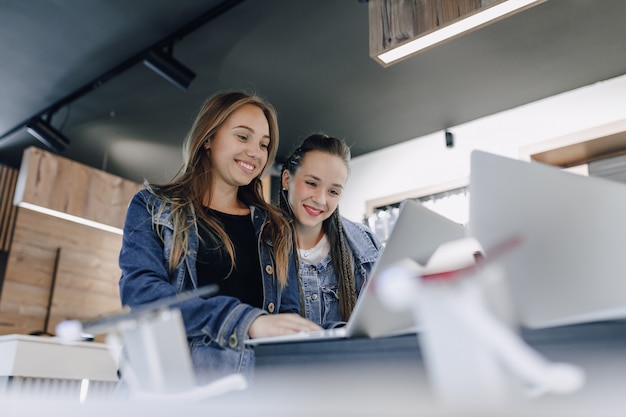 Young attractive girls in an electronics store use a laptop at an exhibition. concept of buying gadgets.