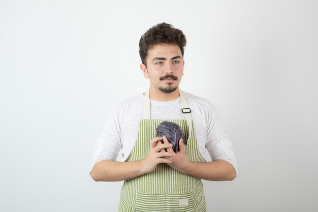 Young attractive guy holding cabbage and looking away.