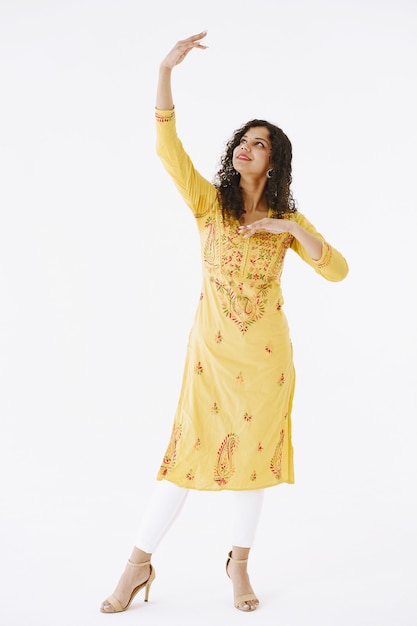 Young attractive Indian woman in traditional dress. Woman dancing against white background.