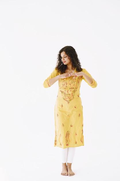 Young attractive Indian woman in traditional dress. Woman dancing against white background.