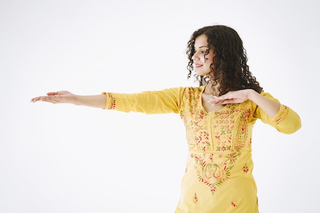 Young attractive Indian woman in traditional dress. Woman dancing against white background.