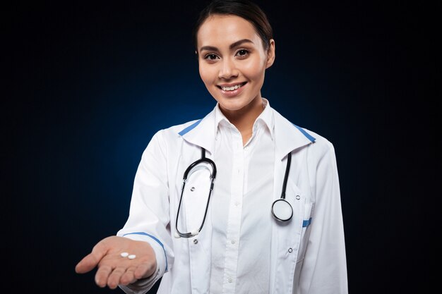 Young attractive lady doctor showing pill and smiling